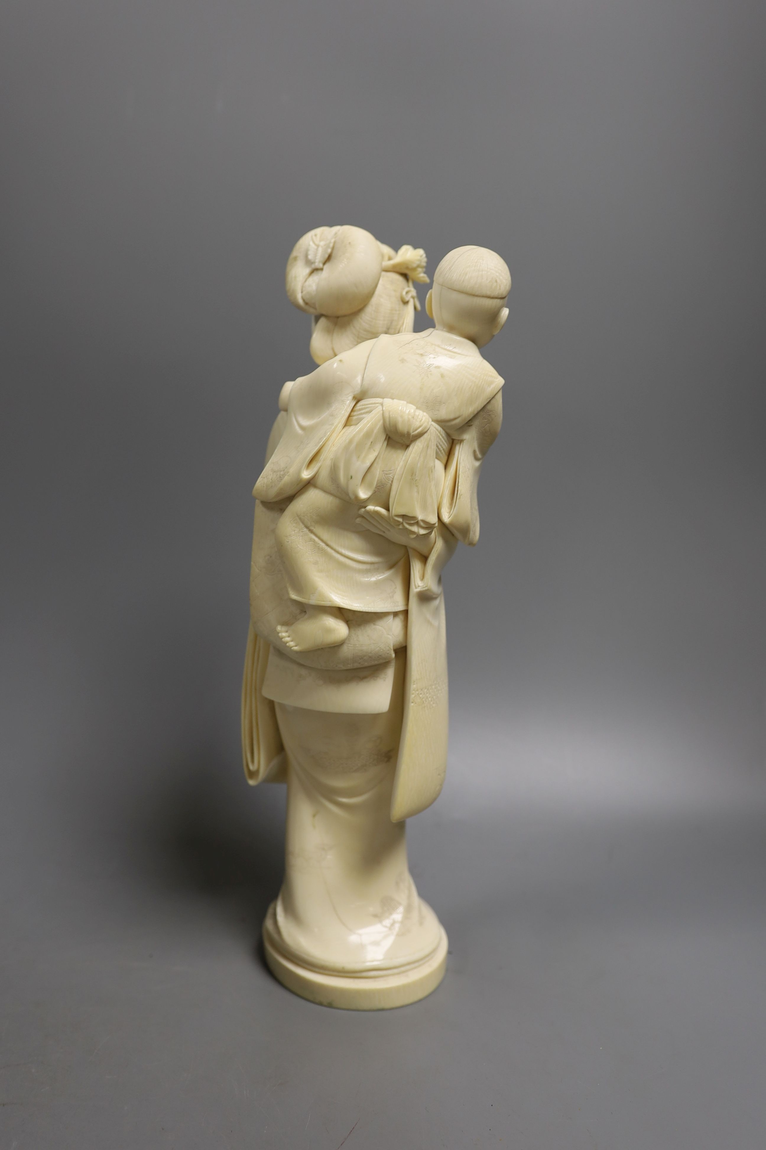 A large Japanese Tokyo School ivory okimono of a lady with child holding a puppet, Meiji period, 31 cms high.